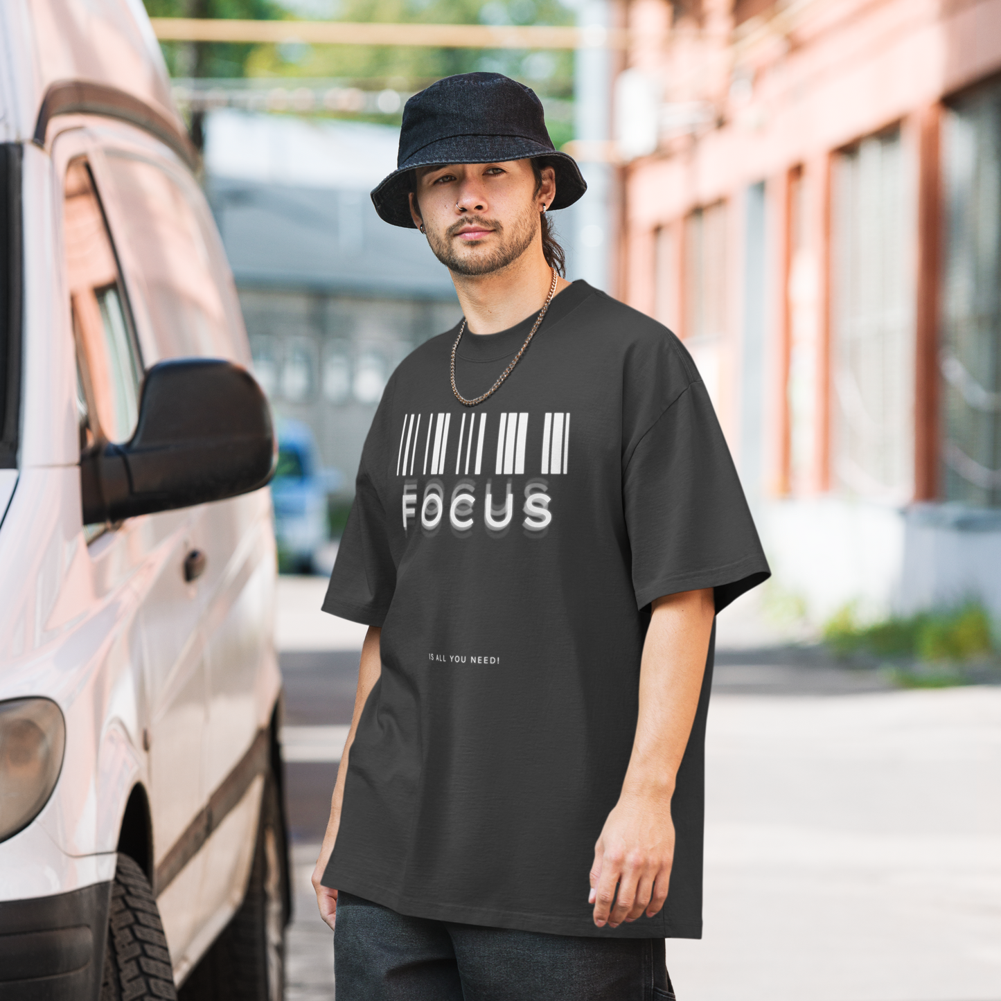 man on street wearing printed graphic oversized shirt in black colour with print saying, "focus is all you need"