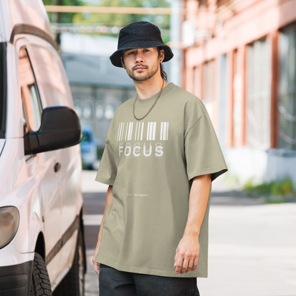 man on street wearing graphic oversized shirt in faded eucalyptus colour with print saying, "focus is all you need"